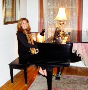 Susan J. Fischer sitting on piano bench in her New York studio